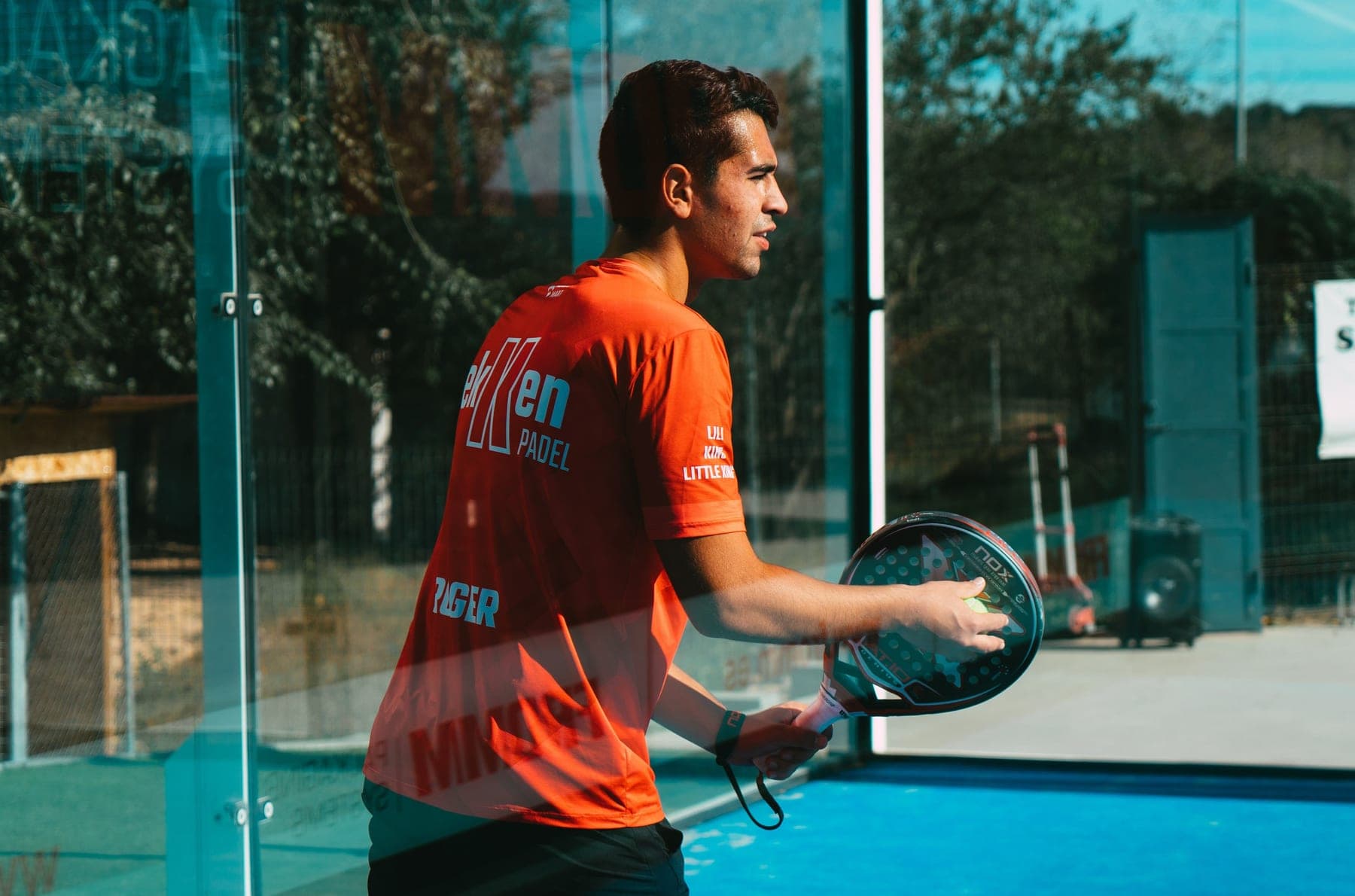 Padel racket and ball on the artificial turf of an enclosed padel court