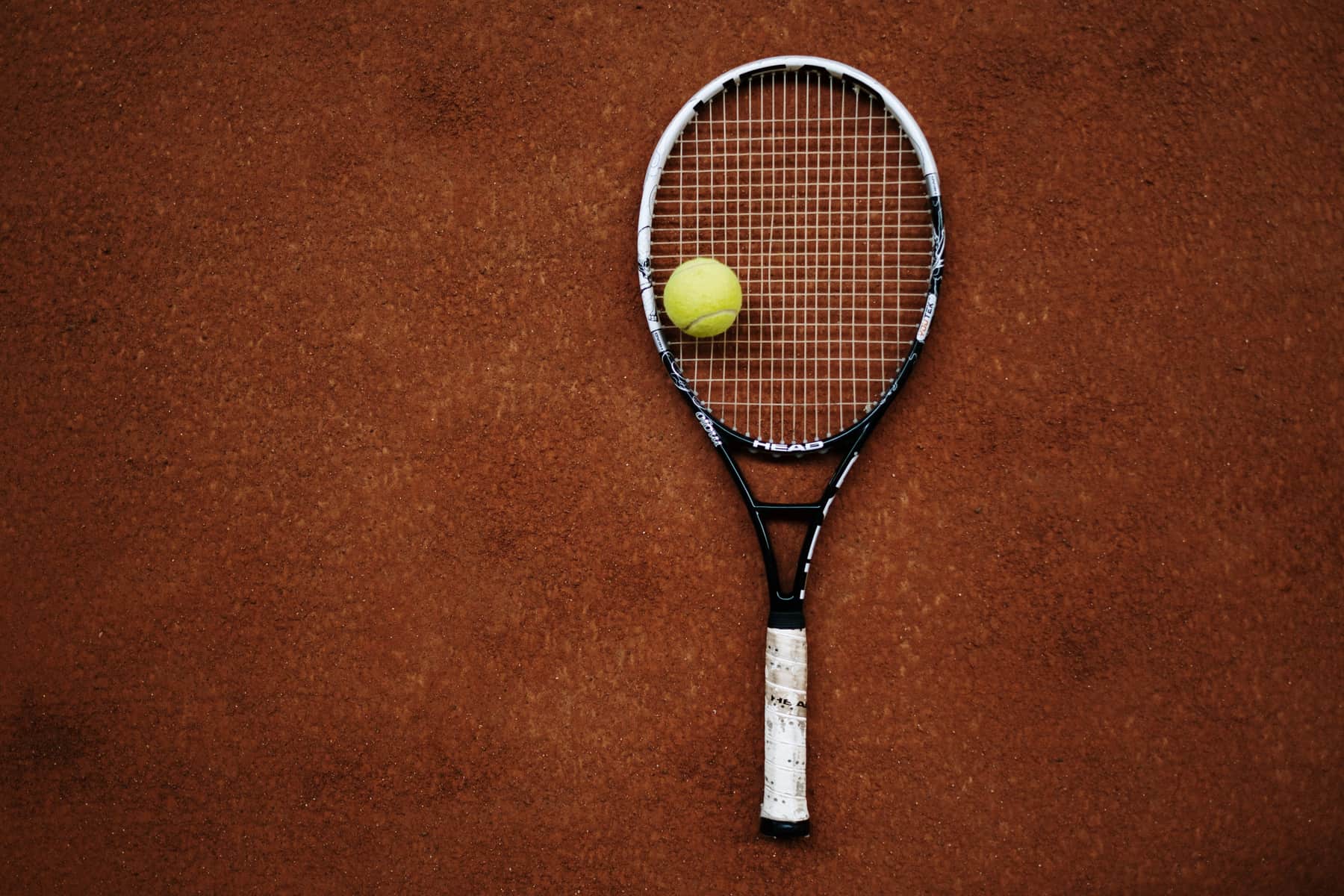 A single tennis racket photographed against a plain court backdrop