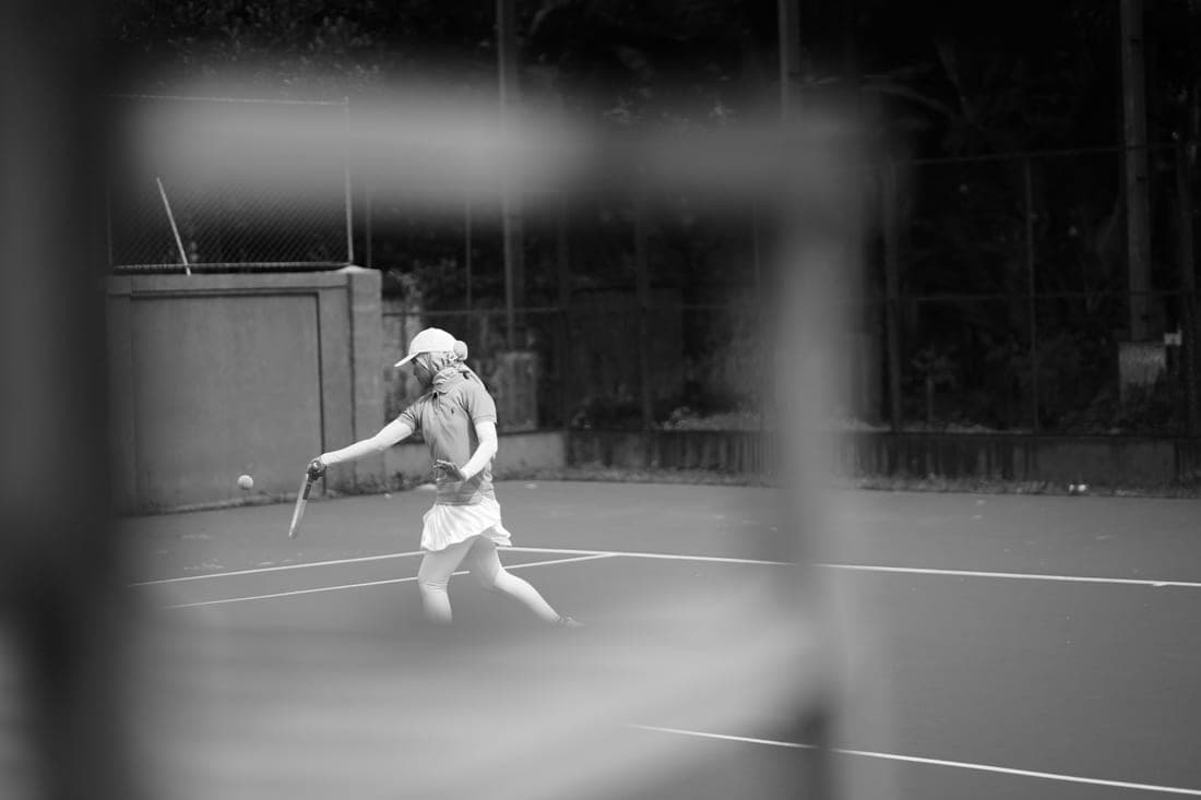 Tennis racquet bag standing upright beside a court bench