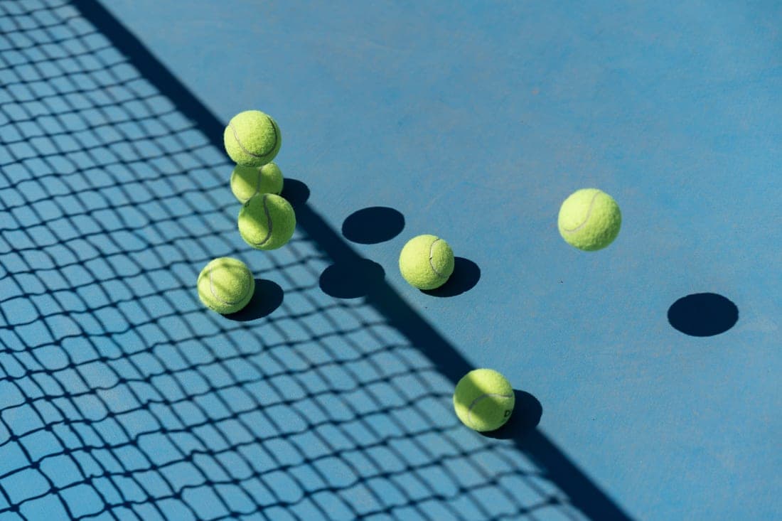 Tennis balls on a hard court beside the service line