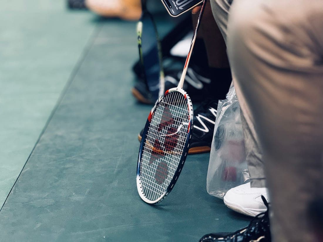 Racquet bag packed with rackets standing against a court fence