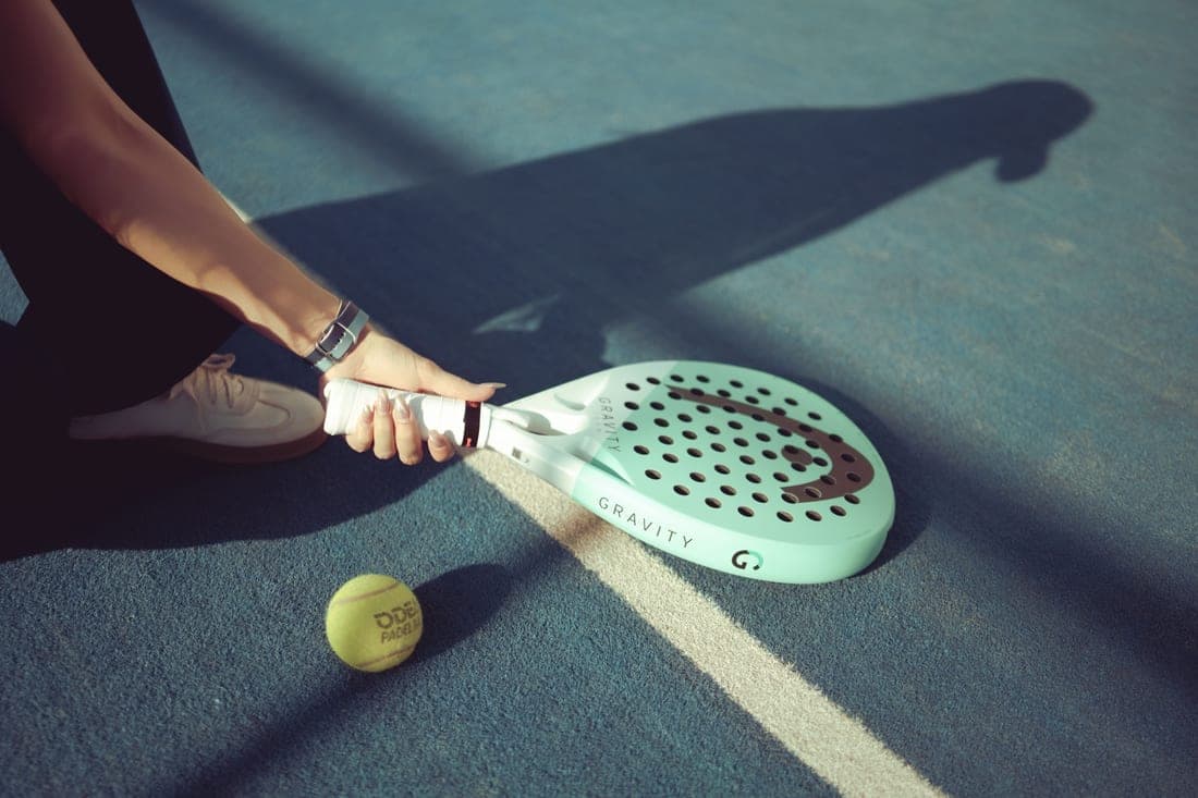 Padel racket and ball on the surface of an enclosed padel court