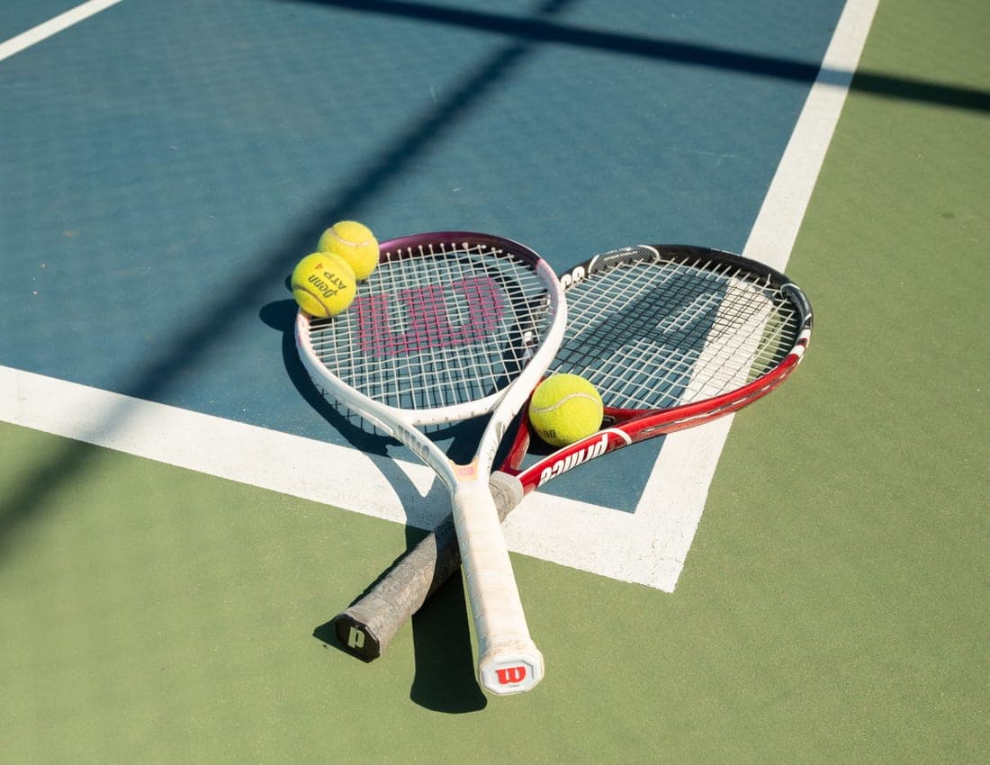 Tennis racket and balls laid out on a painted hard court surface