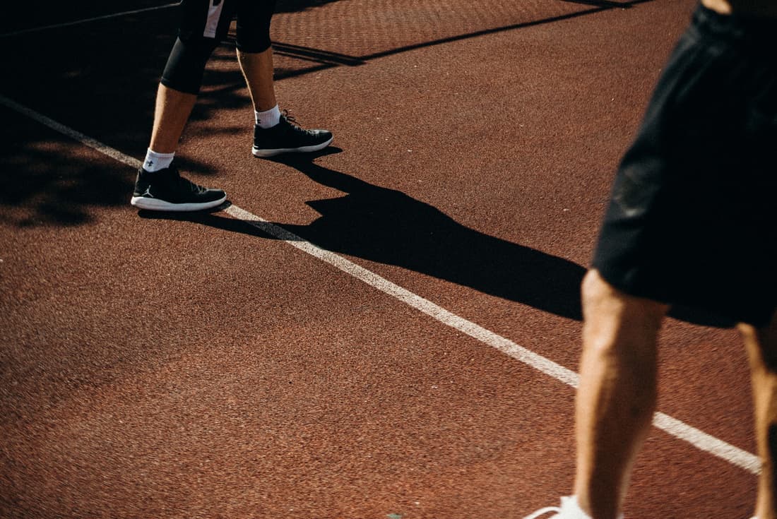 Tennis shoes beside a baseline in hard directional light