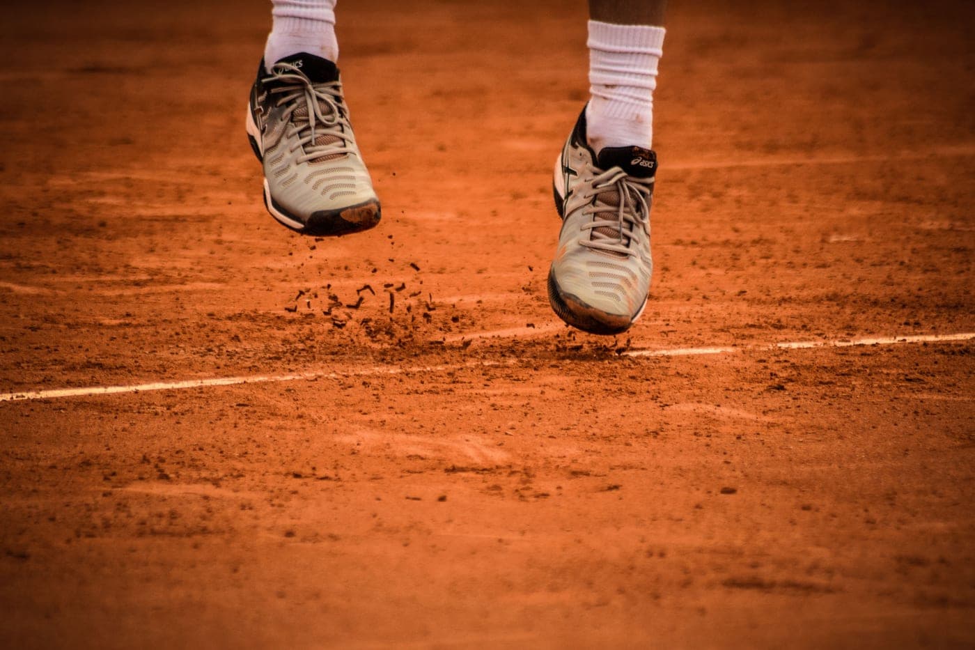 Court shoes standing on a sanded artificial turf surface