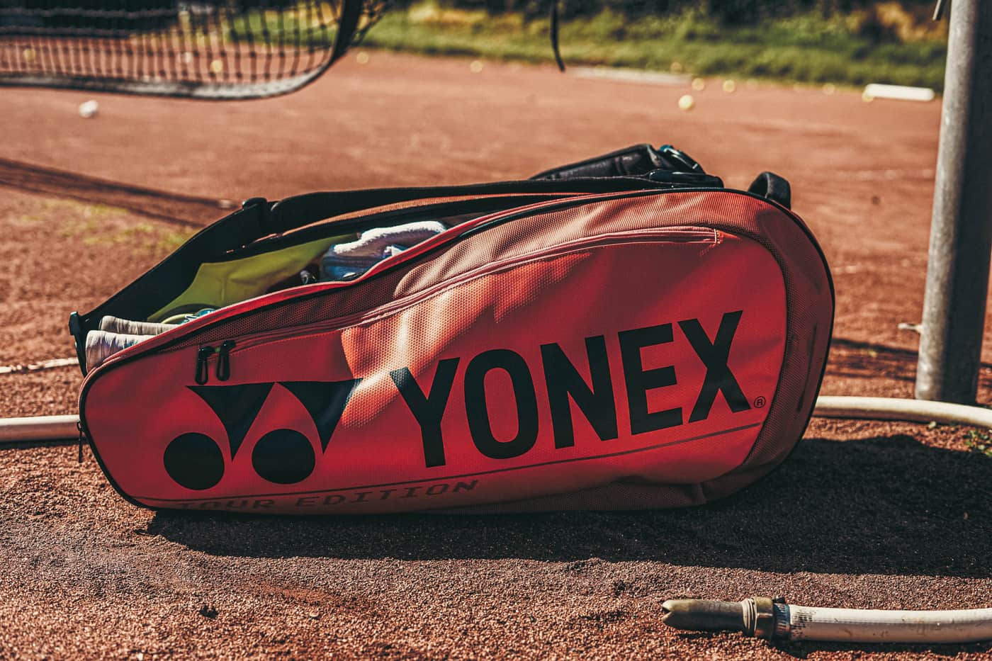 A tennis racket bag resting on a courtside bench