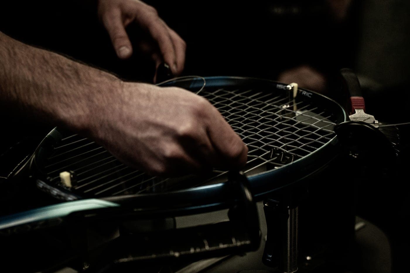 A tennis racket mounted in a stringing machine