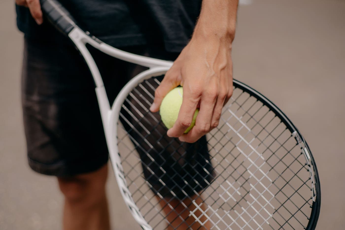 A hand gripping a tennis racket handle