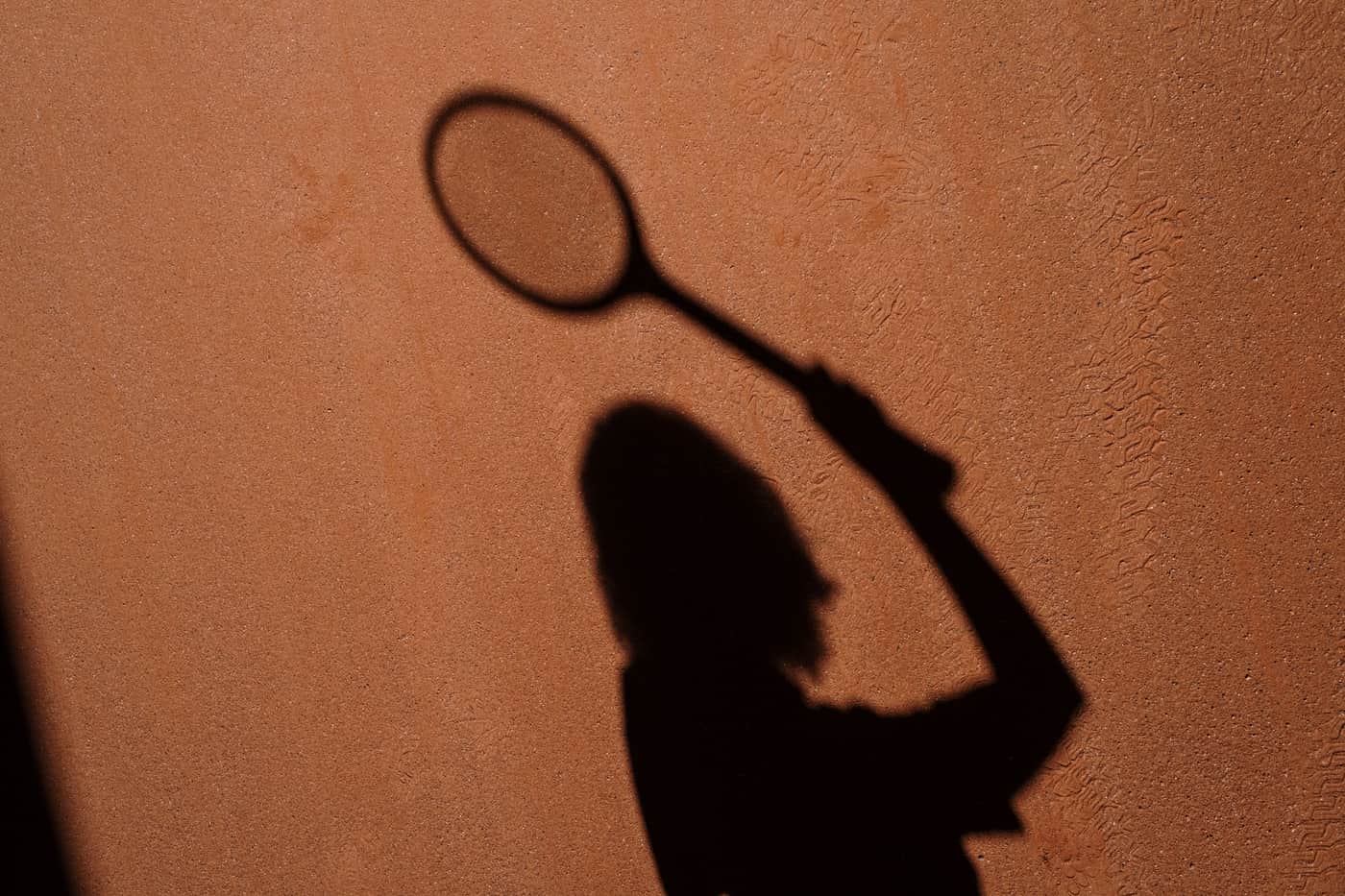 The hoop of a tennis racket silhouetted against the court