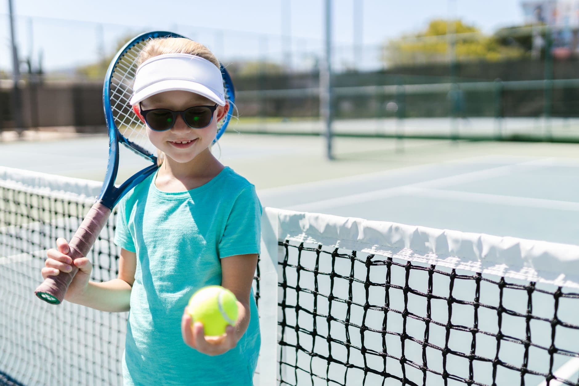A child holding a junior tennis racket on a court