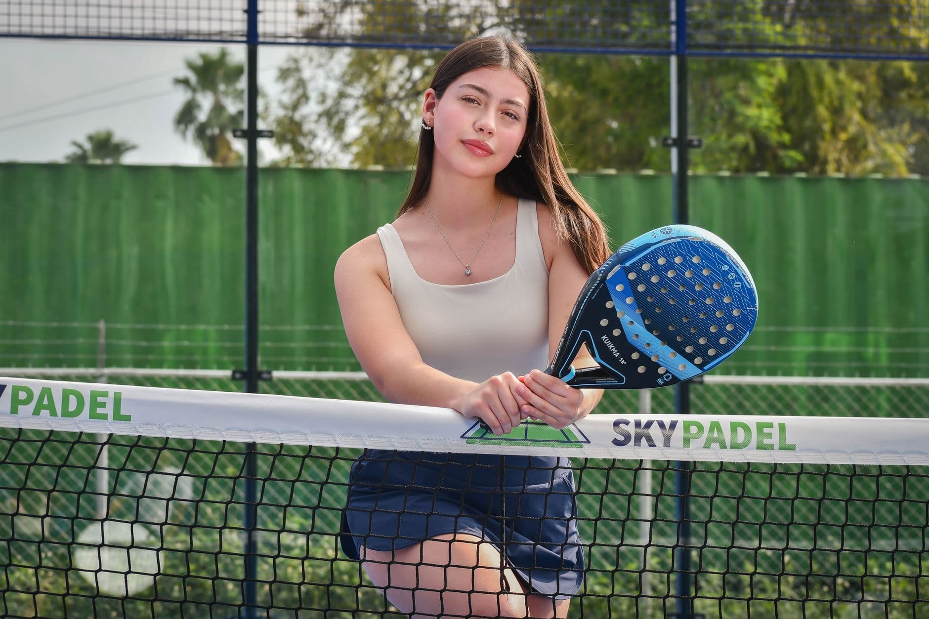 A woman striking a padel ball on an enclosed court