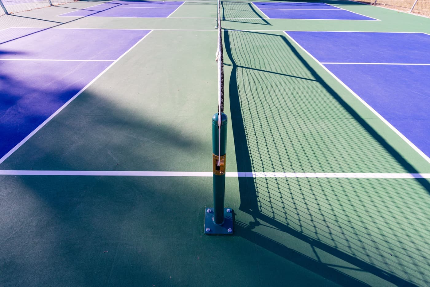 Pickleball court lines and net photographed from the baseline