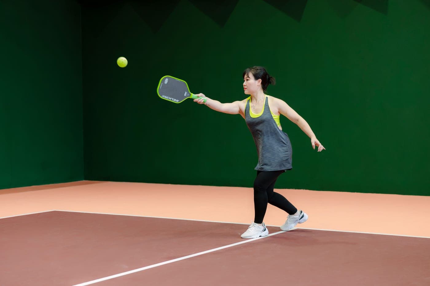 A player striking a pickleball on an outdoor court