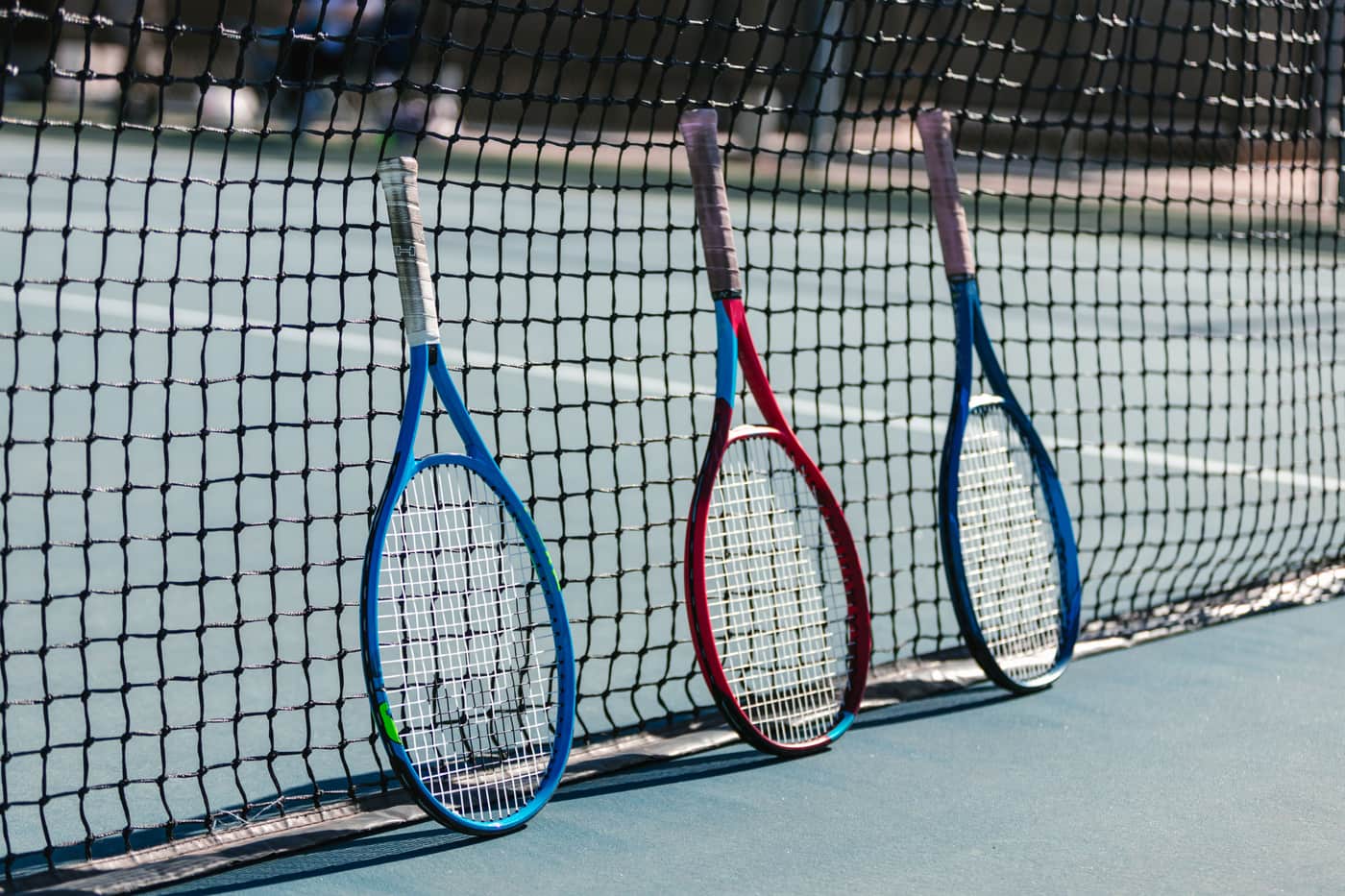 Several entry-level tennis rackets laid out on a court surface