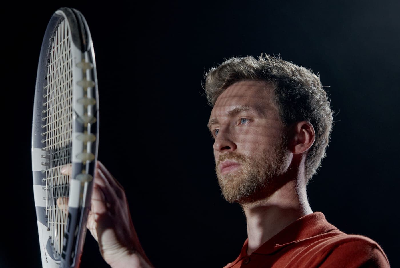 A thin-beam control racket photographed against dark court paint