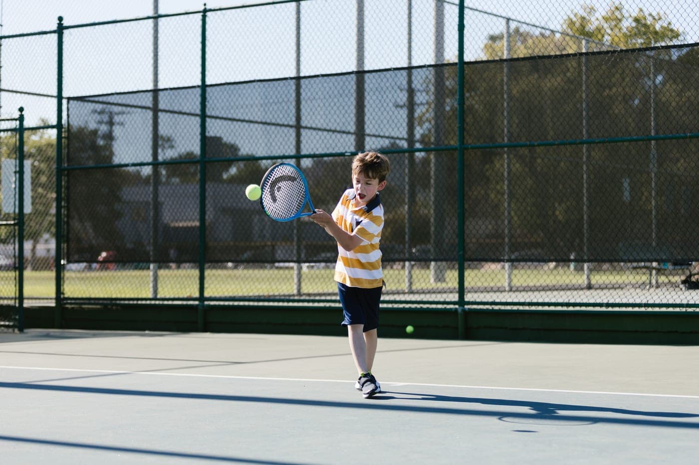 A shorter junior tennis racket resting beside a full-size adult frame