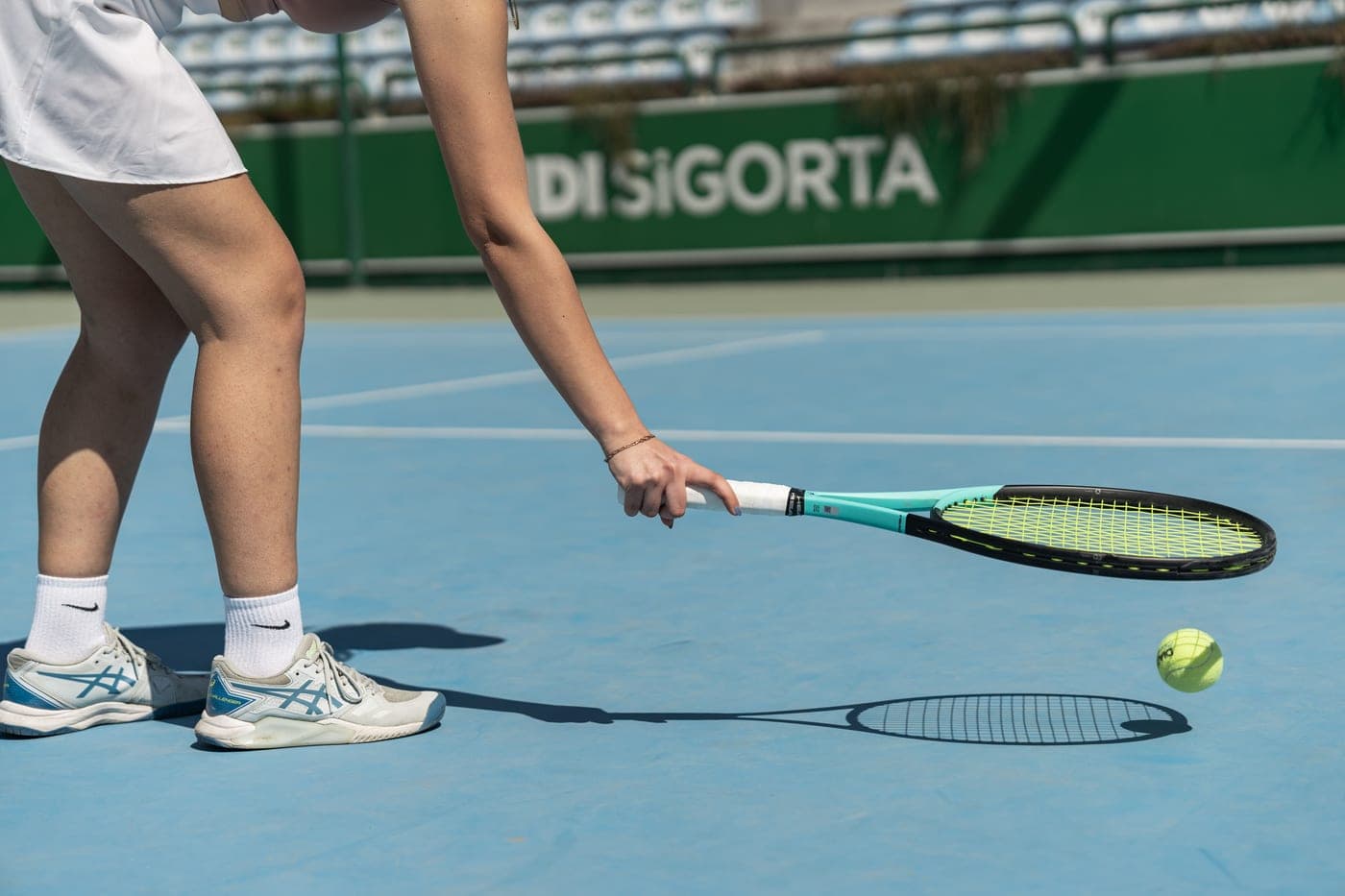 A lightweight tennis racket held up against a bright court background