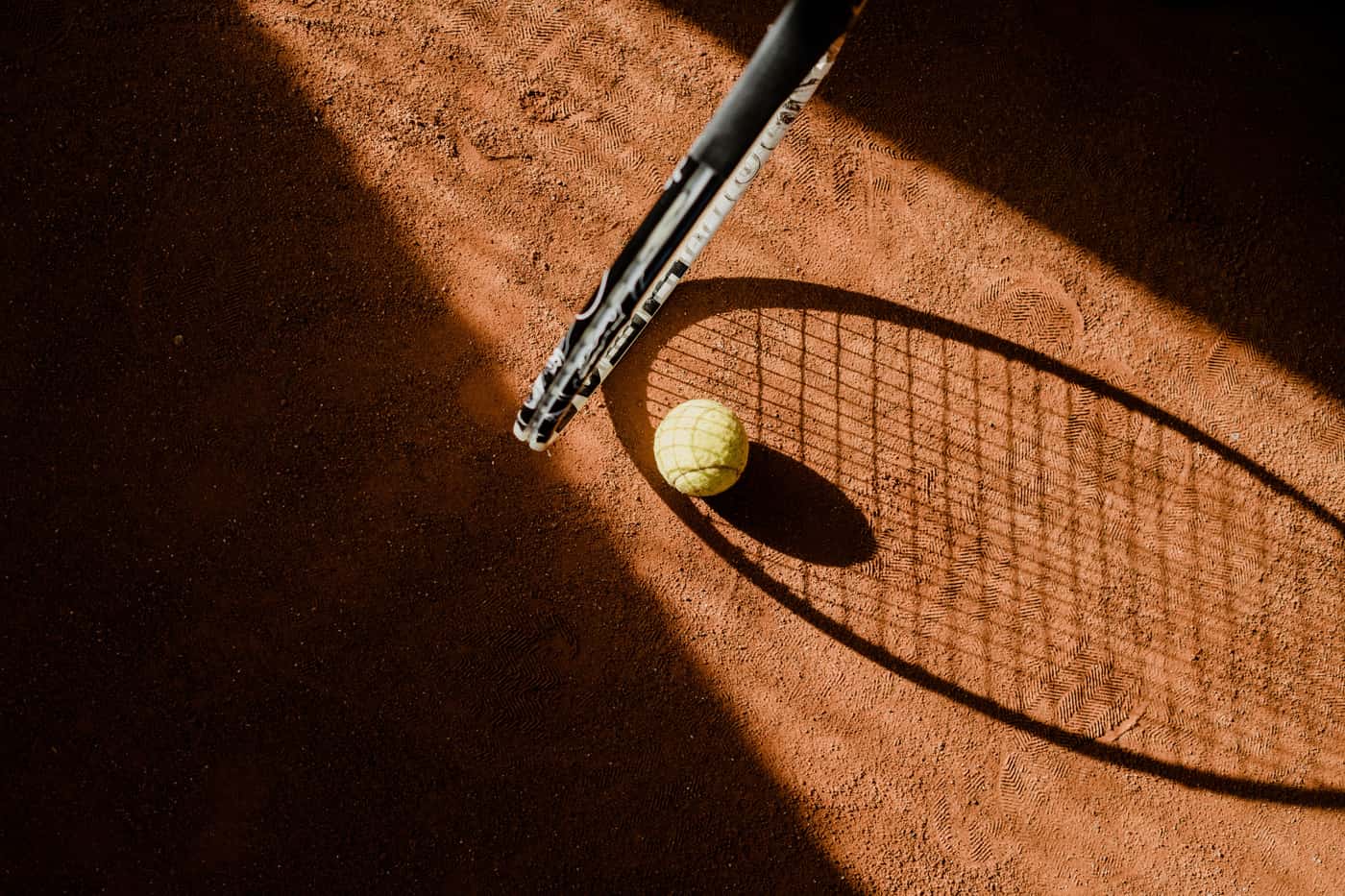 A tennis racket and ball photographed in hard directional light