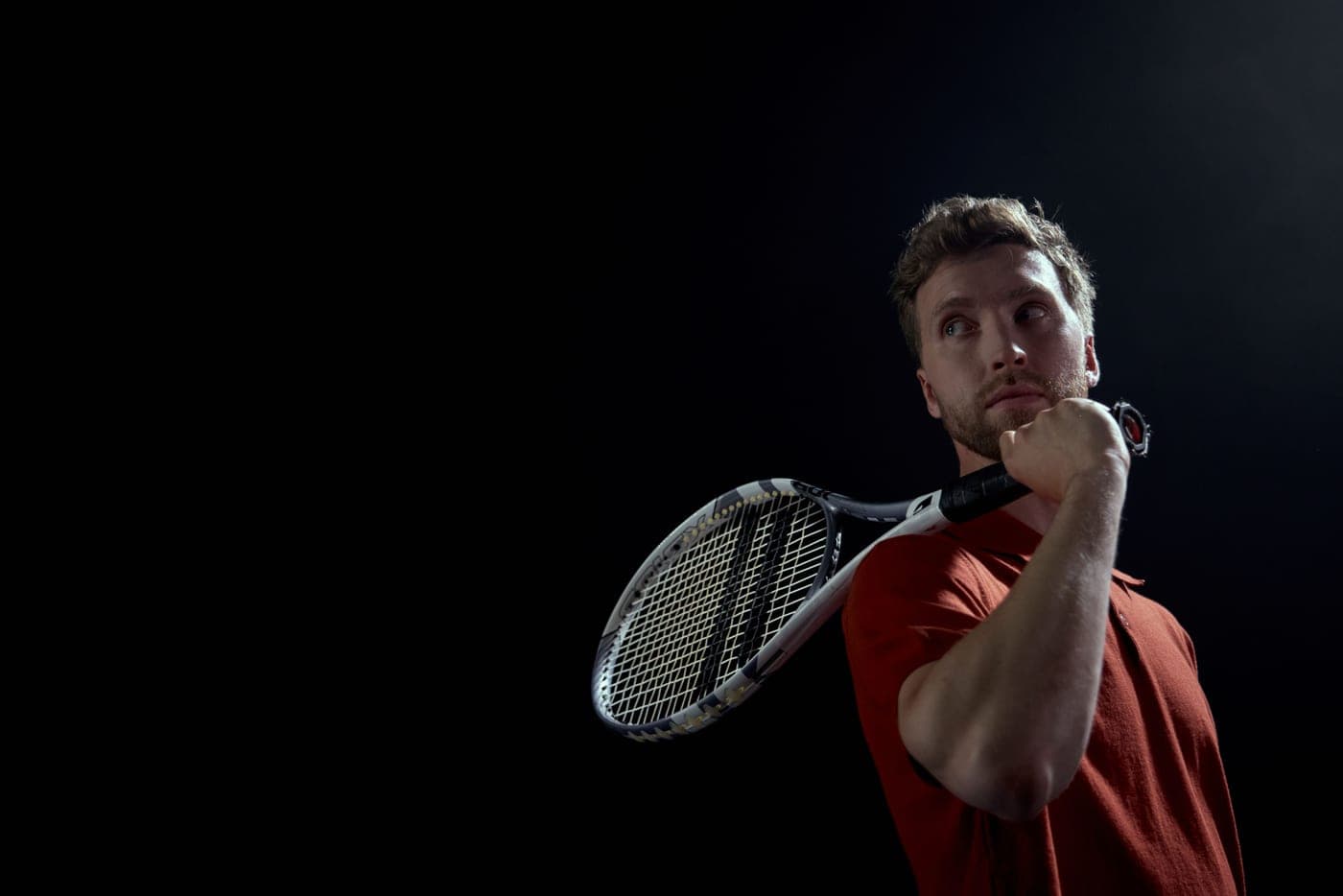 A dark tennis racket photographed against a plain background