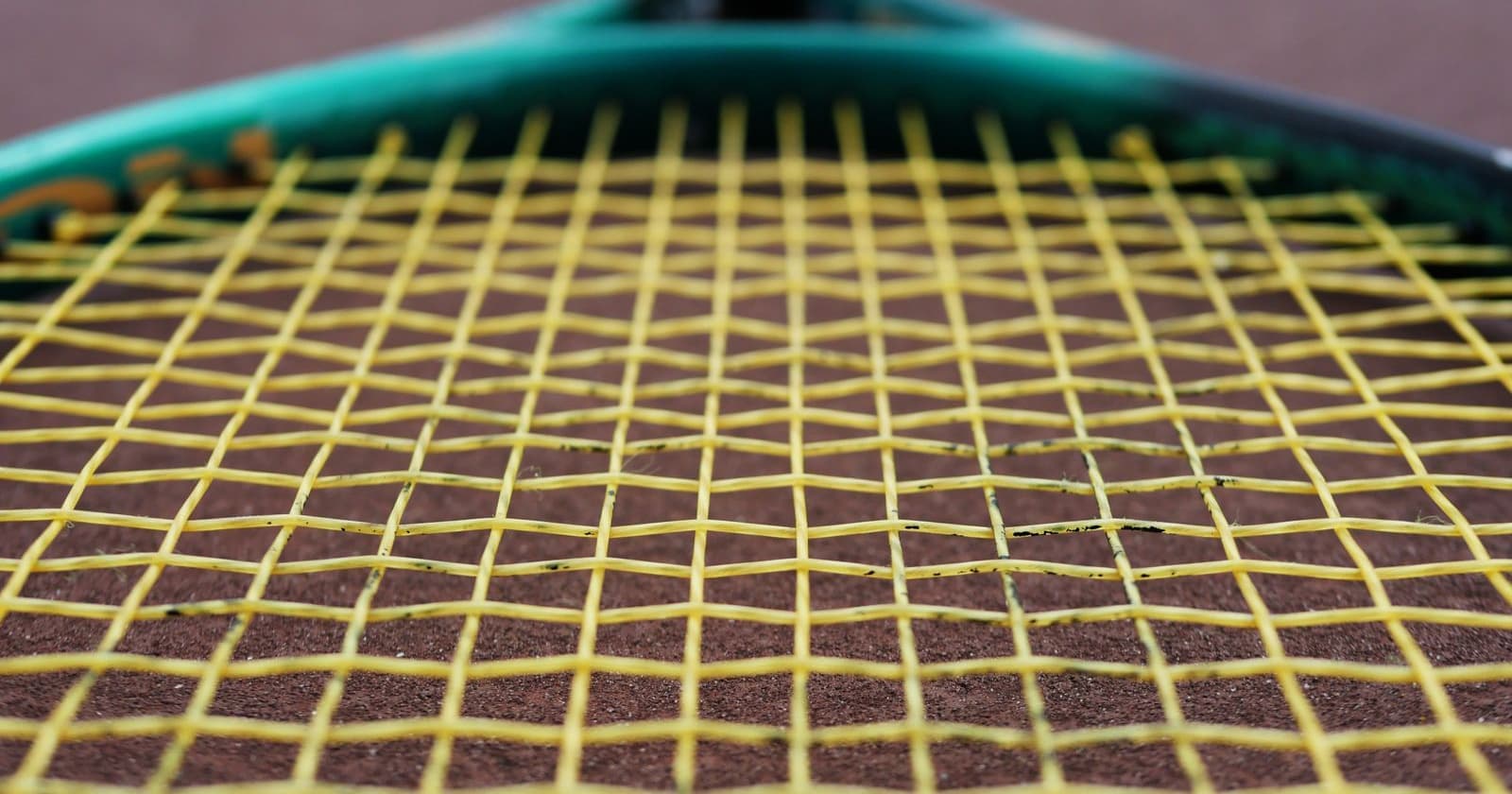 Macro view of a tennis racket string bed with yellow strings