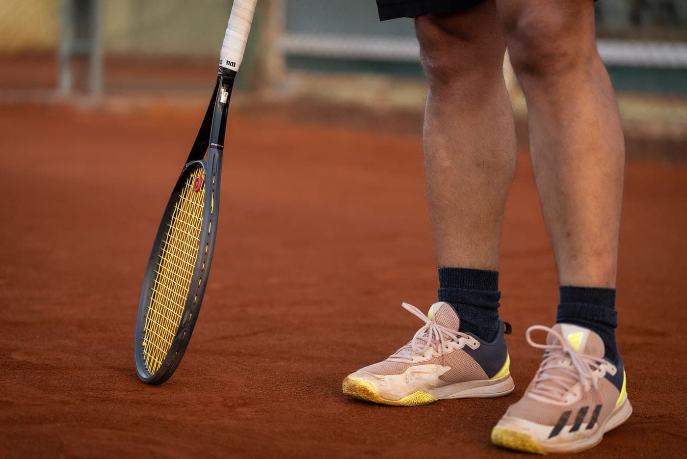 Court shoes on a red clay court with loose surface material